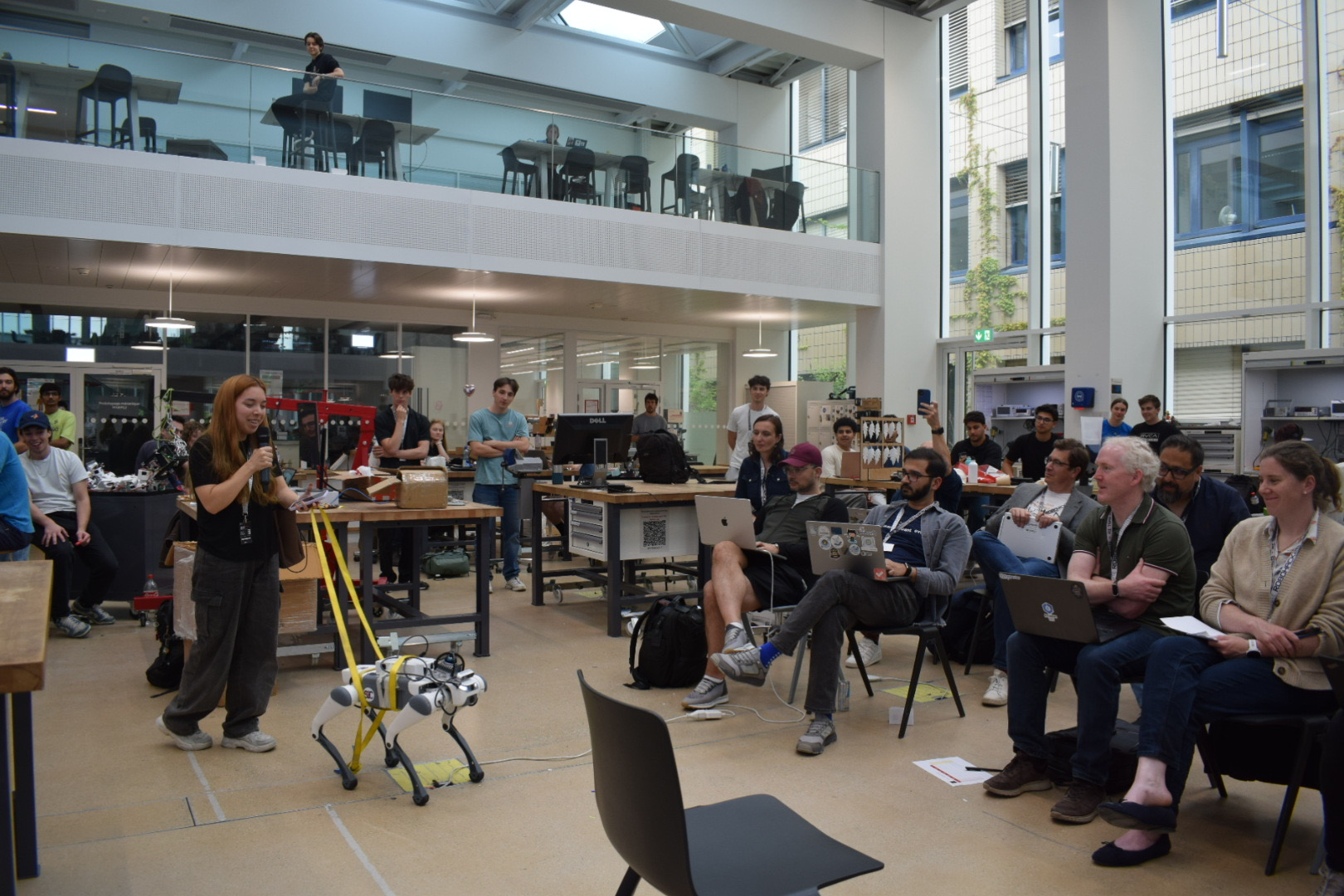 A builder demoing a quadruped robot to a seated audience